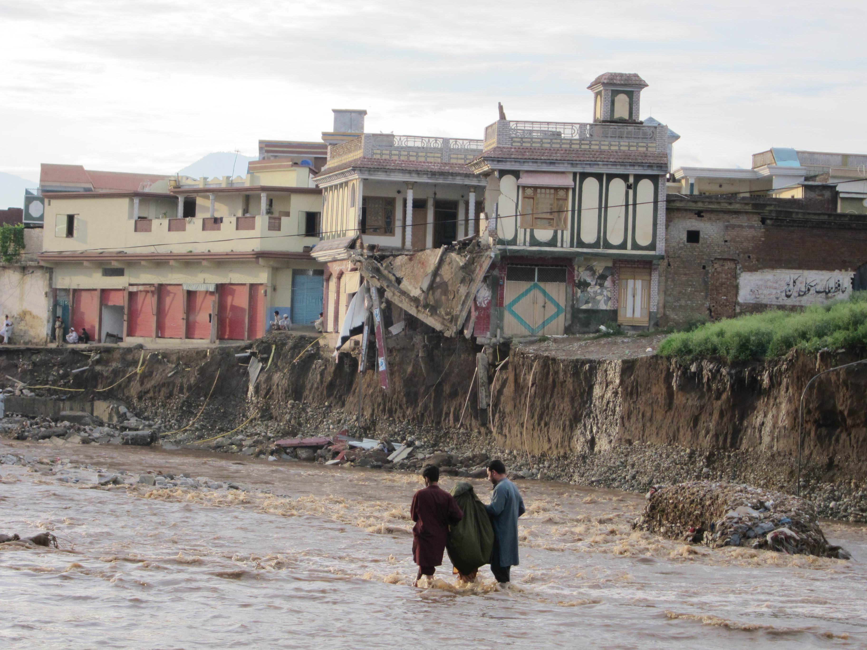 Children walking by a neighborhood destroyed by flooding