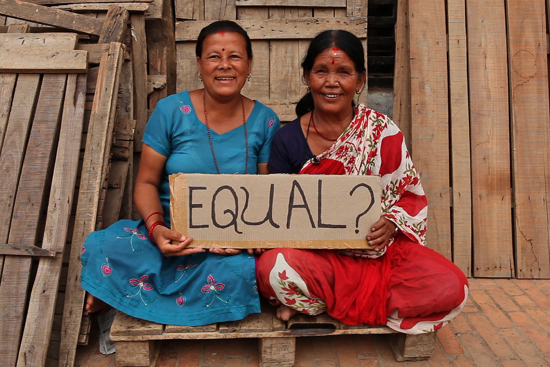 Two women in Nepal hold a sign reading, 